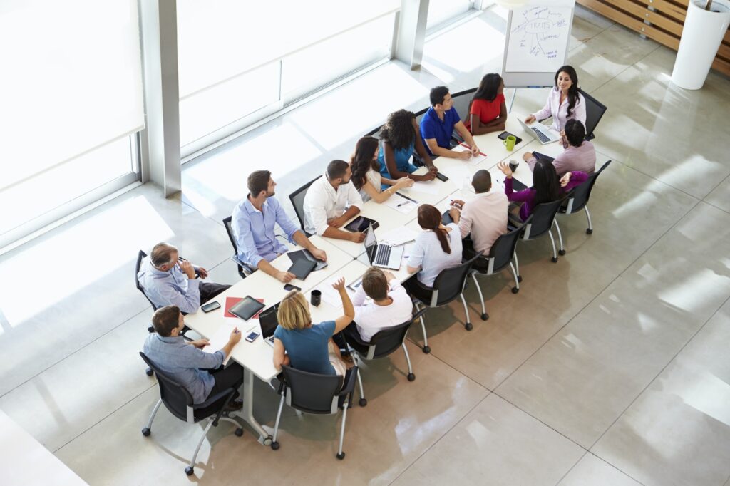 Businesswoman Addressing Meeting Around Boardroom Table