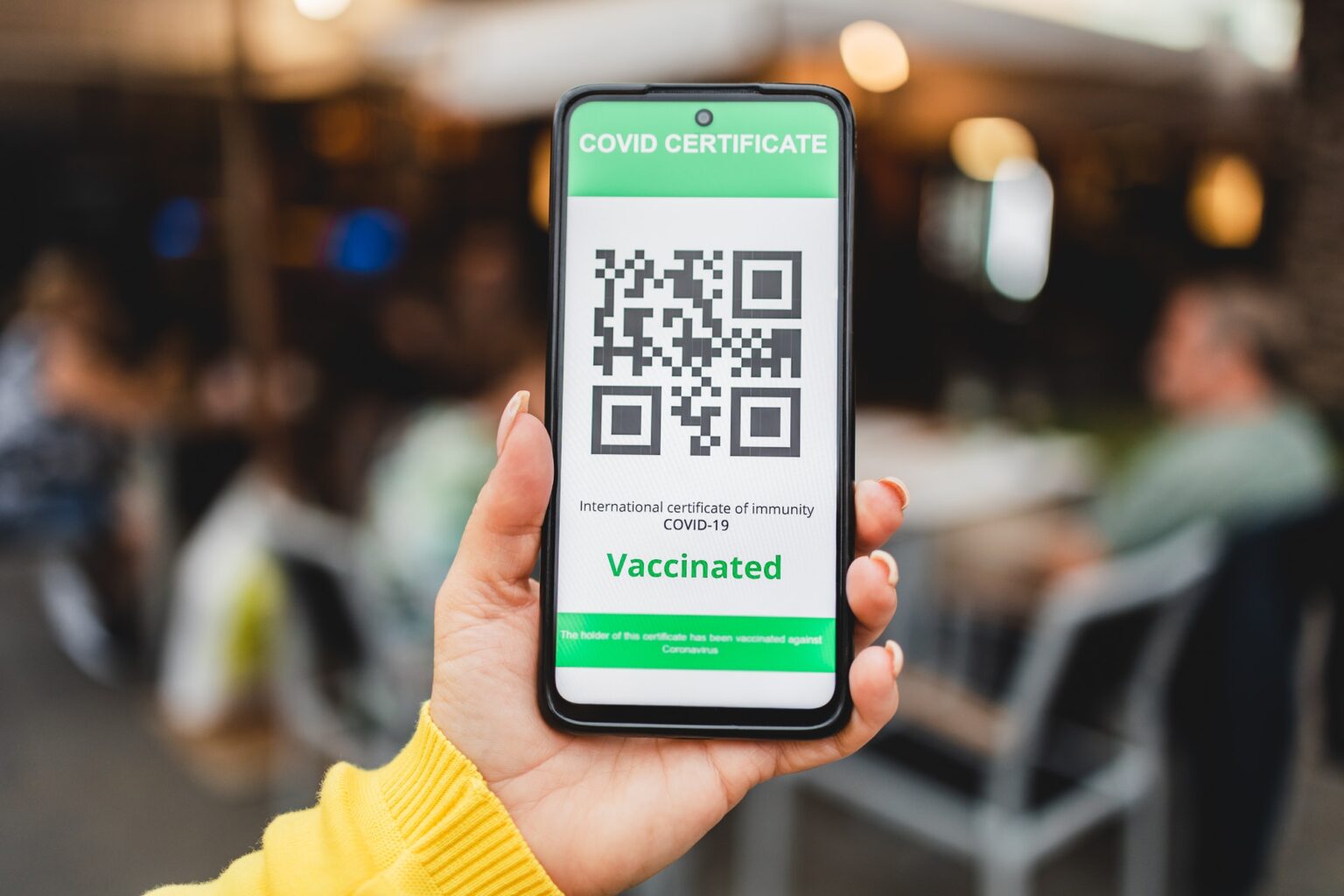 Digital green pass certificate app for coronavirus vaccine with bar restaurant on background